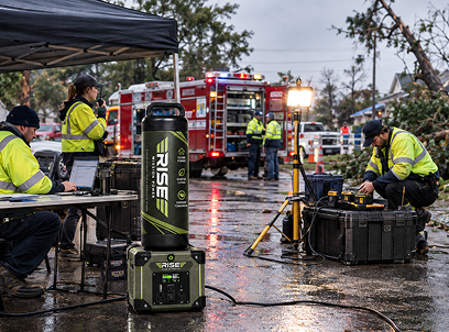 Emergency responders powering laptops and radios from a Rise Mission Power portable system beside a fire truck after a storm